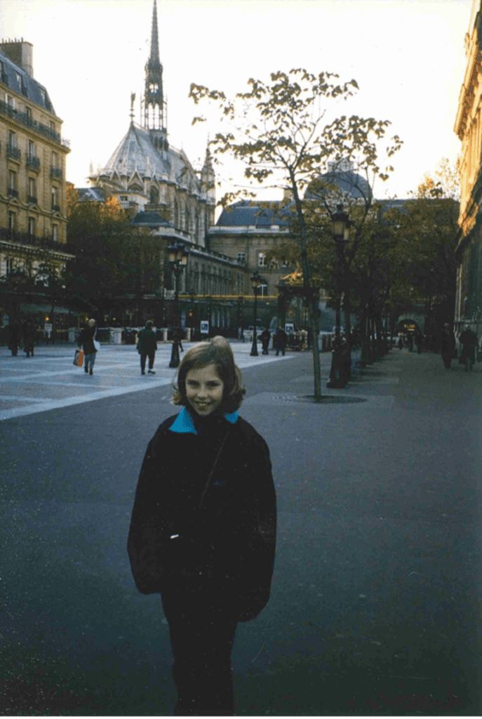 A young girl in a winter coat standing on the street in Paris.