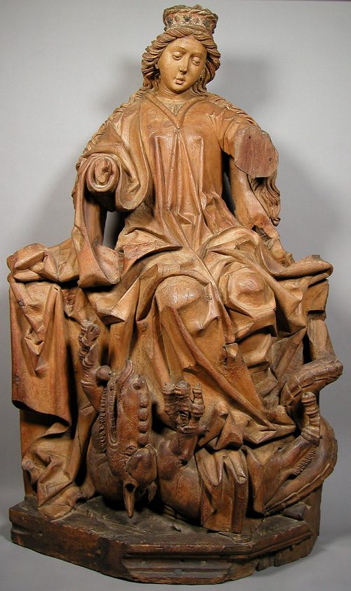 A wood sculpture of a woman rising triumphantly from a dragon’s belly.