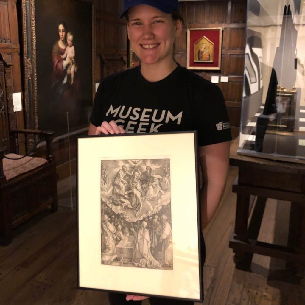 Person in a museum holding a framed black-and-white artwork.
