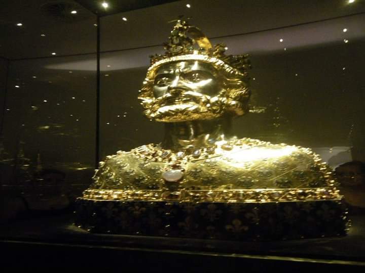 Golden bust of a regal figure in a glass case.