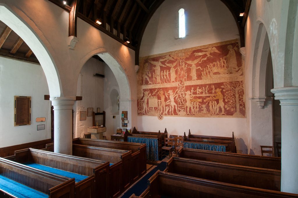 Southwest view of church interior with large mural painting on the west wall, and aisles to the sides. A lancet window is centered above the painting.