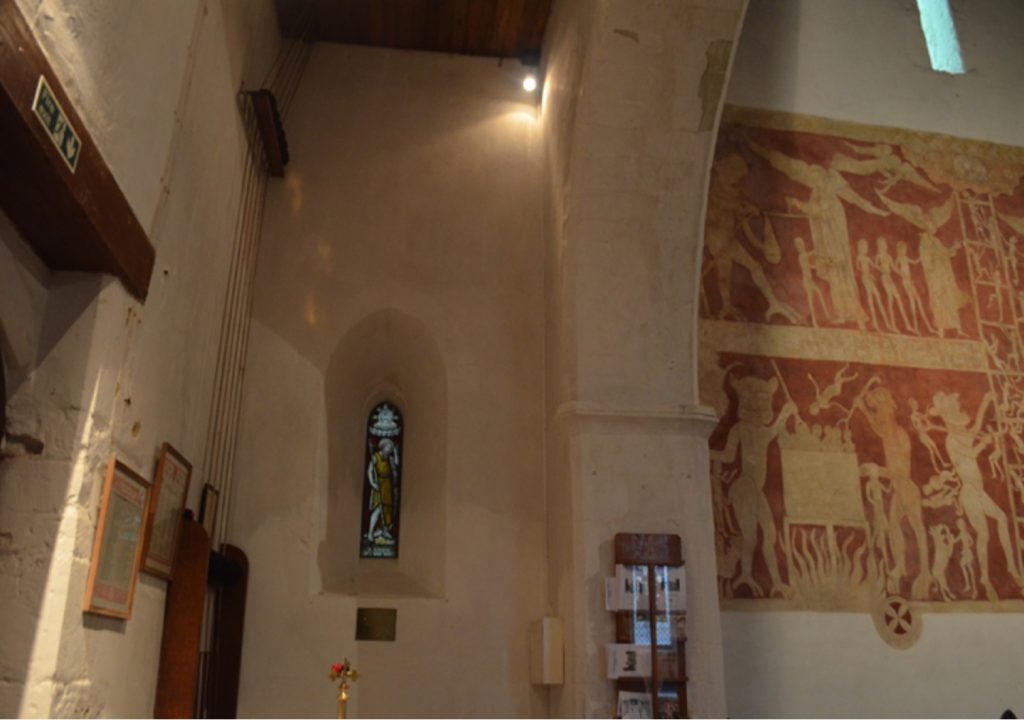 West wall of the south aisle of Chaldon church with a lancet window in it. On the right, part of the mural is in view.