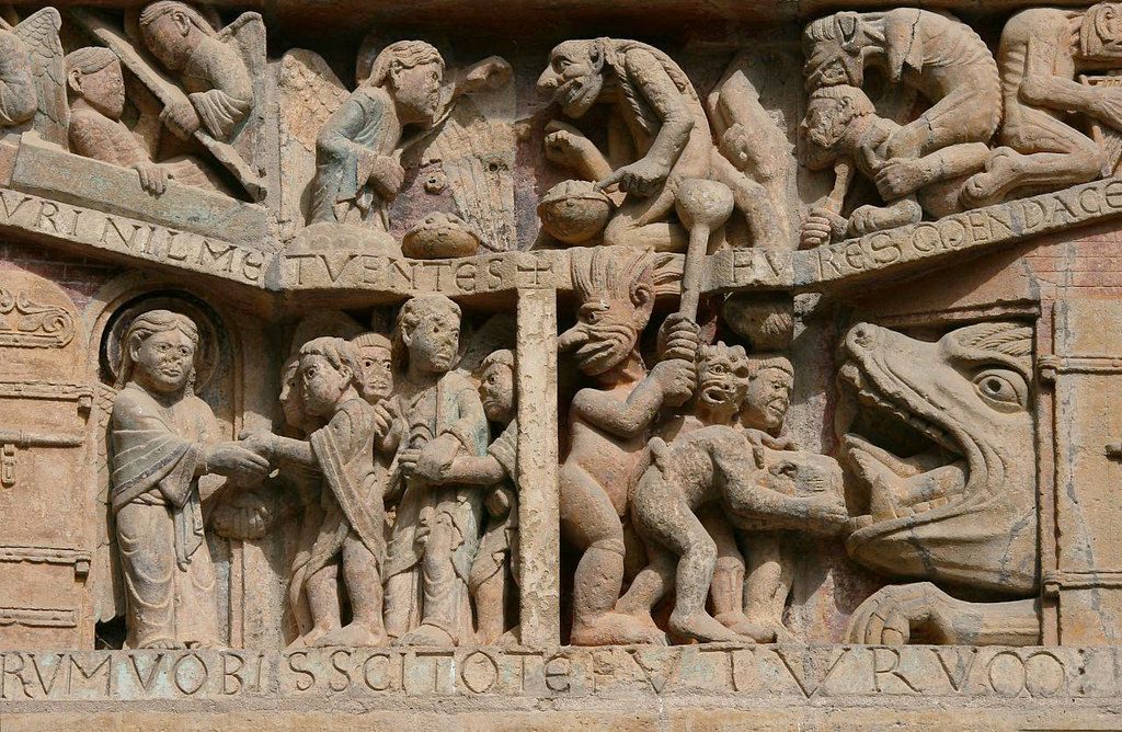 Detail of stone tympanum. On the left, figures are welcomed into a doorway by an angel. On the right, the mouth of hell is being fed figures by a demon.