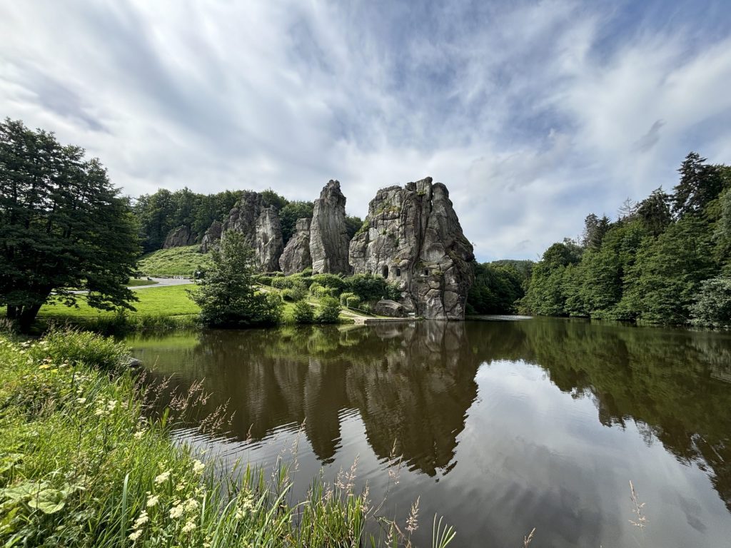 Rock formation towers over a lake and surrounding trees.