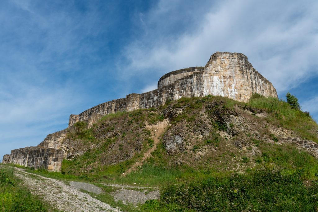 Darkened stone masonry walls atop a grassy hill.