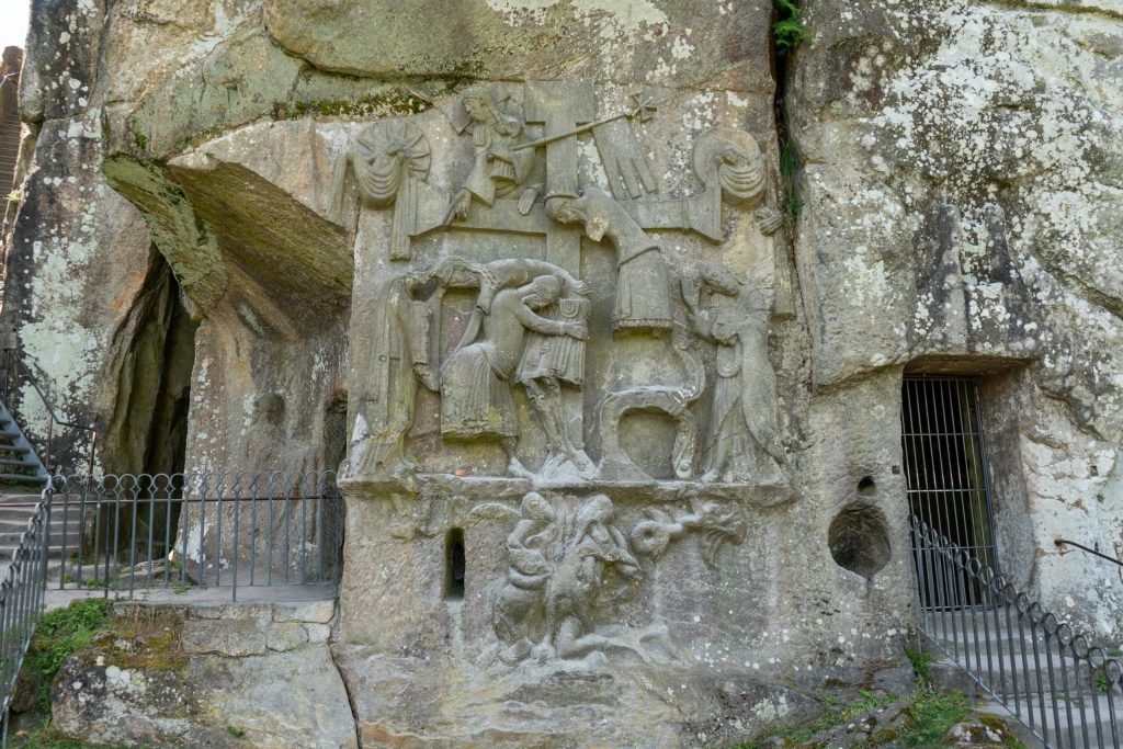Monumental carving into a rock face, centered on a large cross.