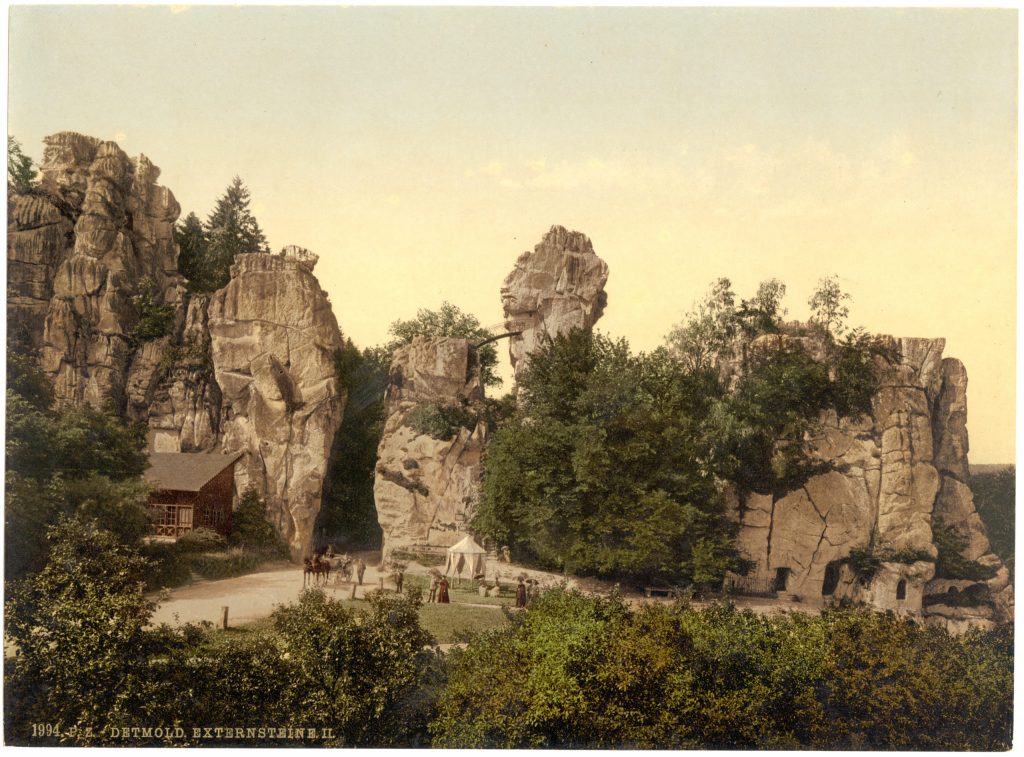 Sepia-toned photograph of people strolling around the large rocks and surrounding trees.