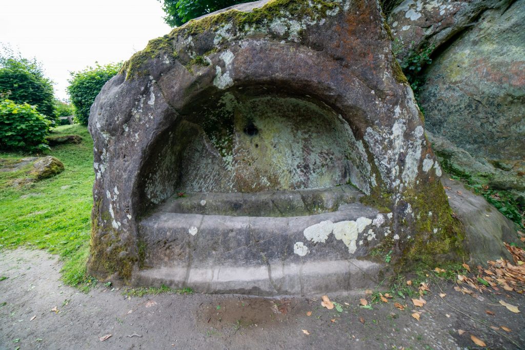 Boulder carved with a human-shaped tomb set within an arch.