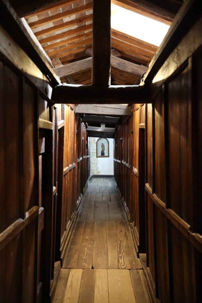 Narrow interior hallway with wooden walls and doors.