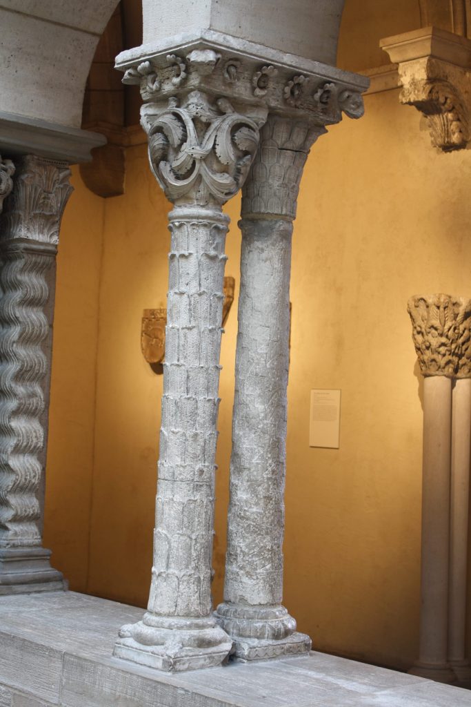 A pair of stone columns, one carved to look like the trunk of a palm tree.