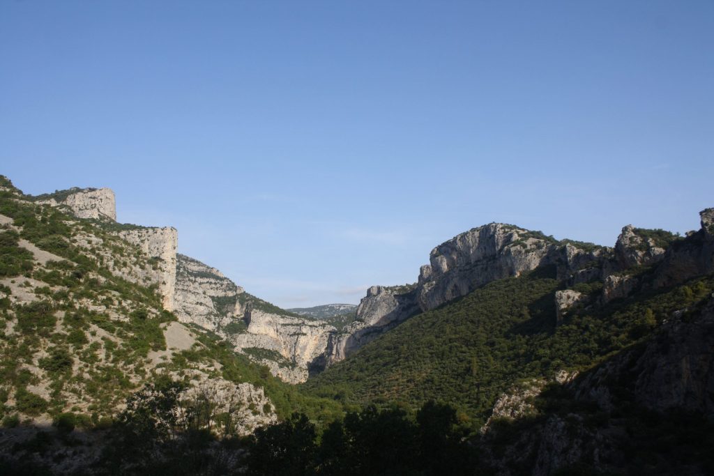 A gorge covered with low vegetation surrounded by stone cliffs.