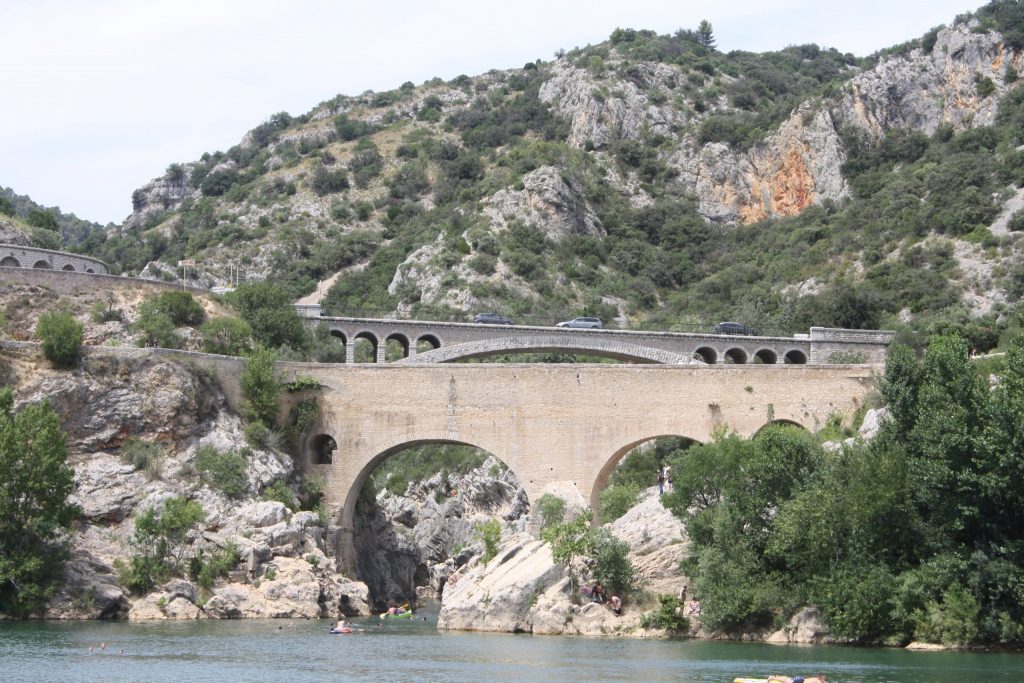 A stone bridge spans a river and a rocky landscape.