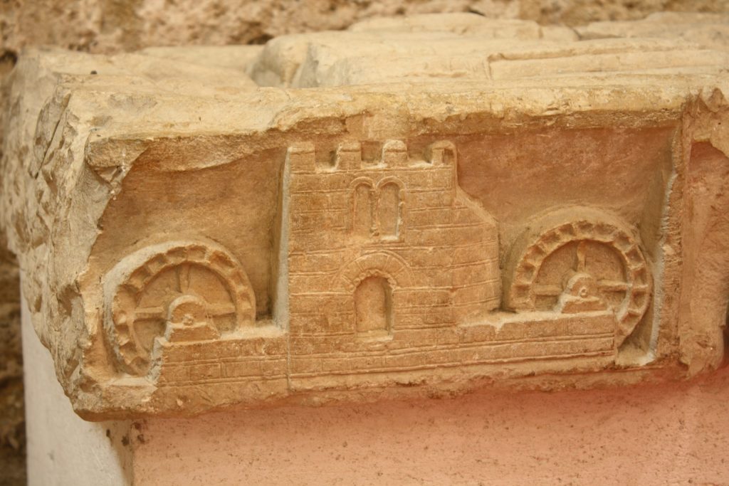 A stone relief sculpture showing a mill with two water wheels.