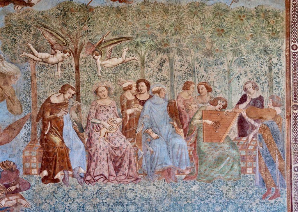 Detail of The Triumph of Death, with a group of well-dressed young people making music and conversing in a garden under orange trees, oblivious to the imminent onslaught of Death, who can just be seen approaching from the left.