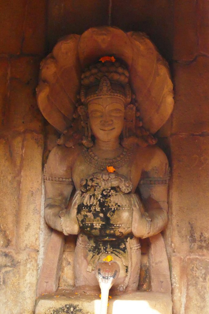 Stone sculpture of a naga, with human torso and snake hood, holding a vase of plenty. Bhubaneswar, Odisha.
