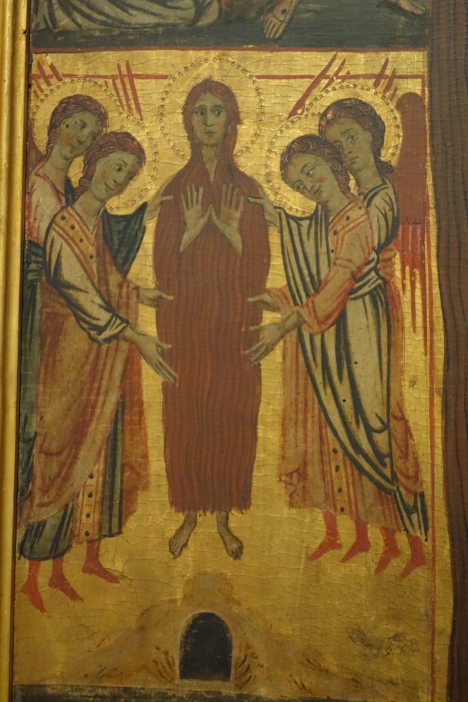 In a detail from the Accademia Vita Panel, Mary Magdalen is elevated in the sky above her cave by four angels, 2 on each side. She is frontal, covered only in her hair, and her hands are raised in front of her chest in an orant pose.