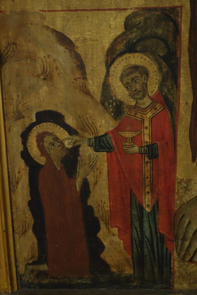 A detail from the Accademia Vita Panel, which shows the scene at bottom on the left, with the Magdalen kneeling at the mouth of her cave receiving Last Communion from St. Maximin.