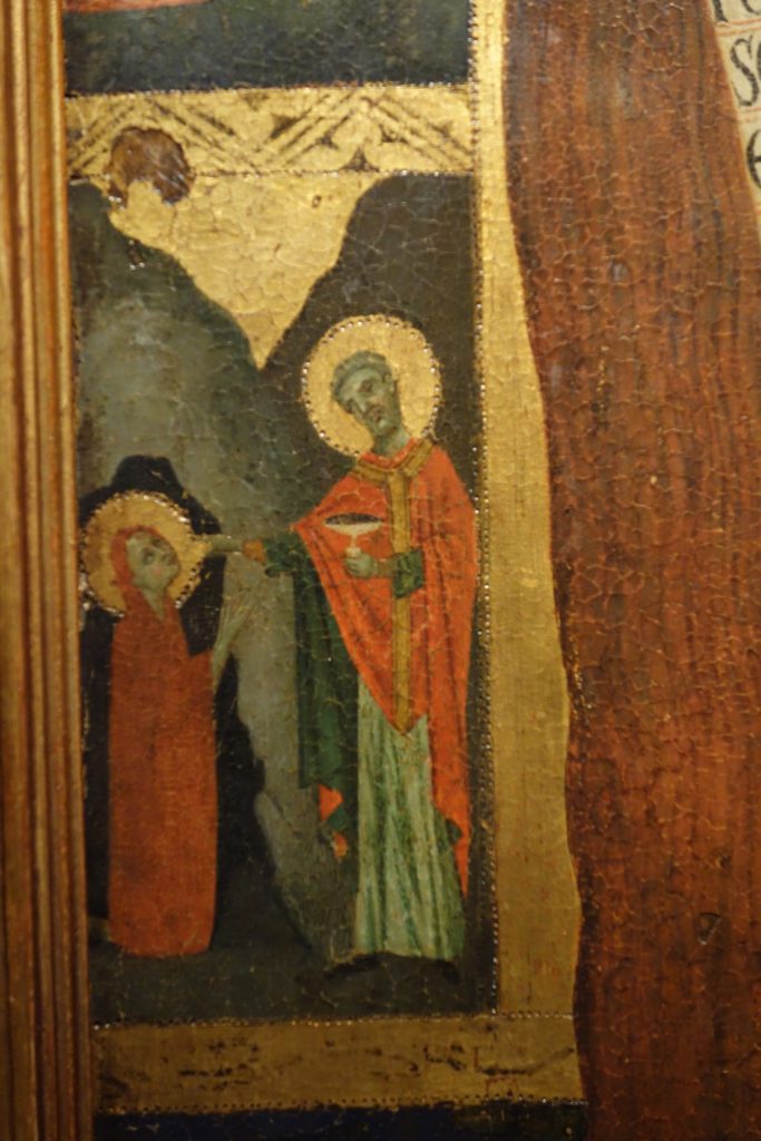 A detail from the Private Collection Vita Panel of the scene at bottom left. It is almost identical to the previous image (Fig. 14), with the Magdalen kneeling at the mouth of her cave receiving Last Communion from St. Maximin.