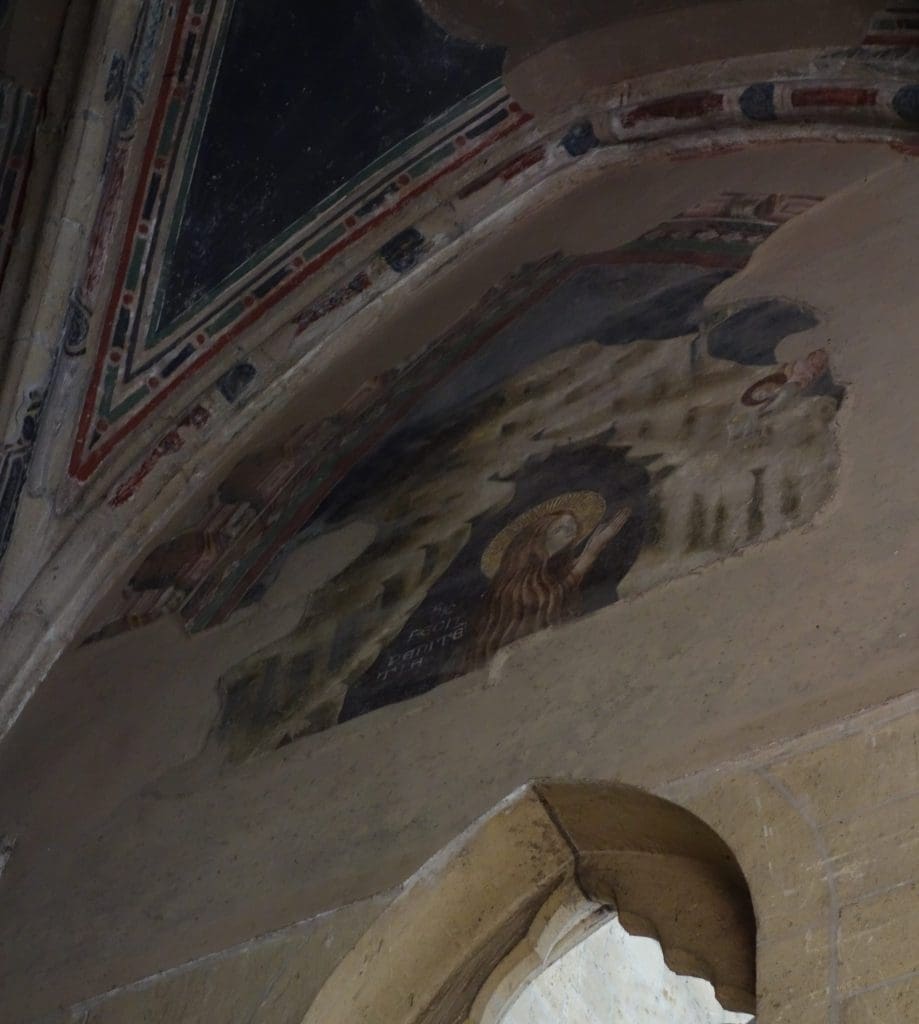 The fresco in the lunette on the right wall of the chapel in San Lorenzo with the Magdalen facing right, kneeling in the mouth of her cave receiving Communion from an angel who is flying in from the left. There is an inscription reading SIC FECIT PENITĒ/[N]TIA[M] or “so she did in penitence.”
