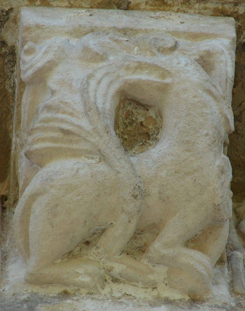 Figure 22. A fantastical corbel beast holds the end of its elaborate tail in its mouth. The tail curls up from between its legs.