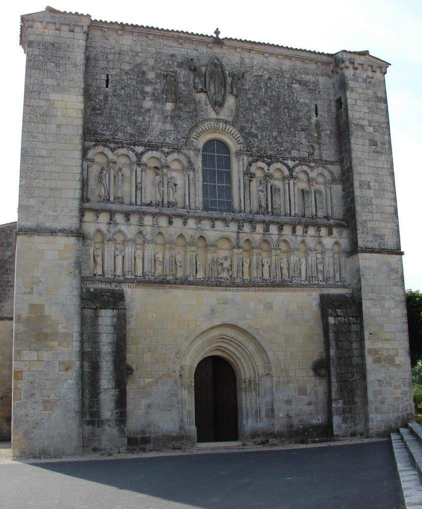 Screen facade of Romanesque church with sculpture and rebuilt areas.