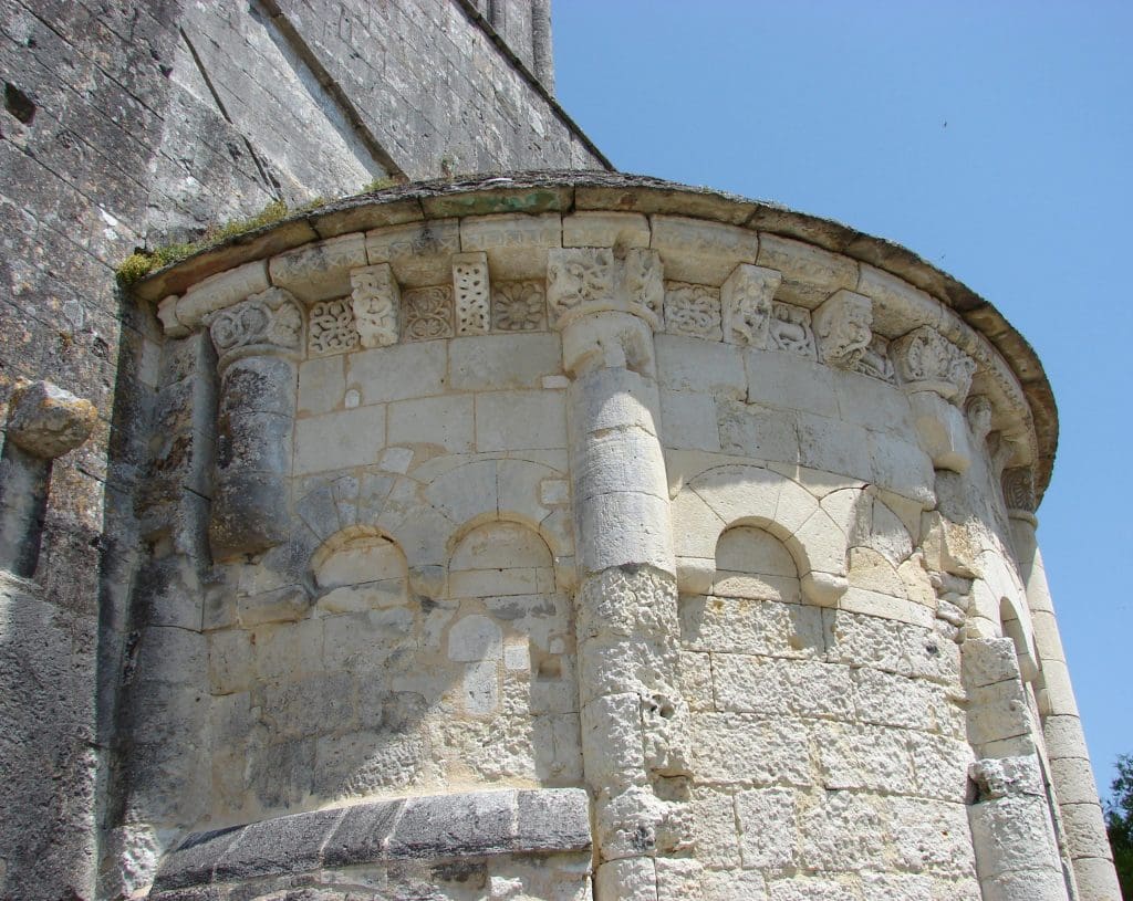 Lobe of a highly sculpted Romanesque chevet with bright blue sky in background.