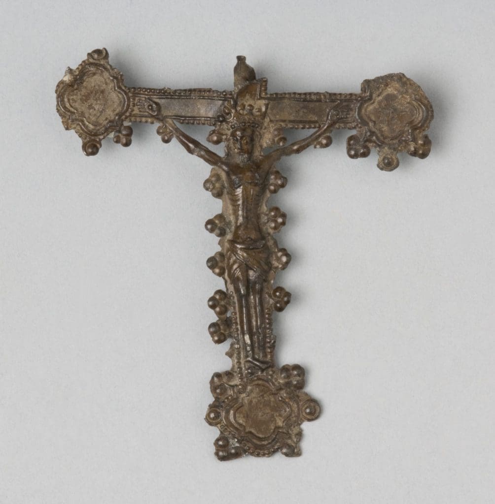 A pilgrim badge showing an image of Christ on the cross.