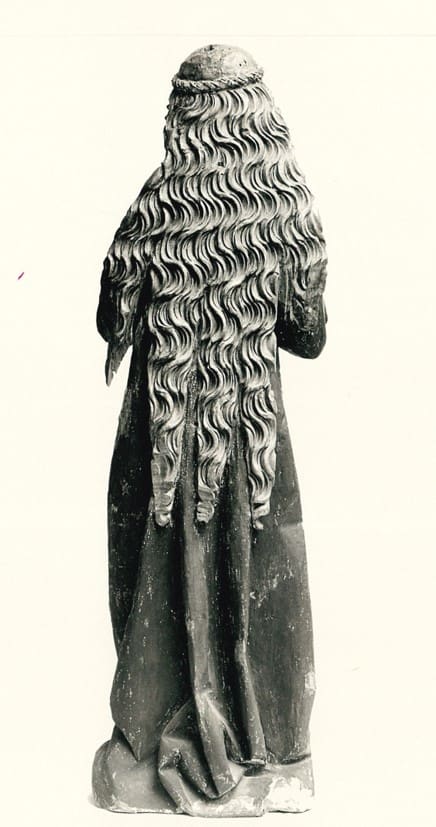 A black and white photograph of a sculpture of a woman with wavy long hair flowing down her back.
