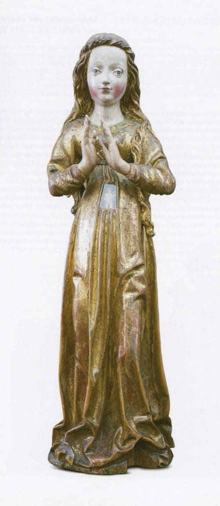 Photograph of a sculpture of a pregnant woman wearing elaborate robes. Her child is visible in a rectangular abdominal cavity, which is closed off by a glass panel.
