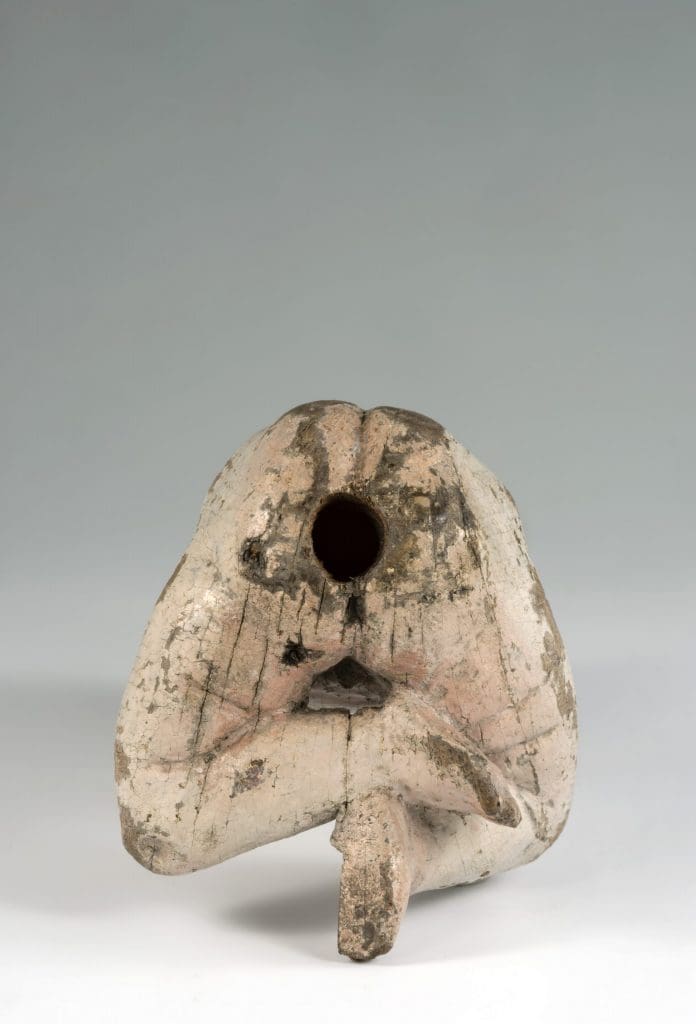 Photograph of a sculpture of a baby showing the underside of the body and the hole attaching it to another figure or a cushion.