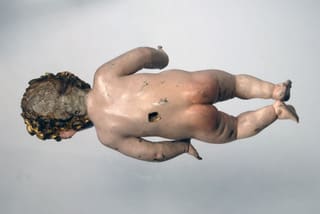 Photograph of a sculpture of a baby representing the Christ child showing the back of the sculpture and the hole for mounting.