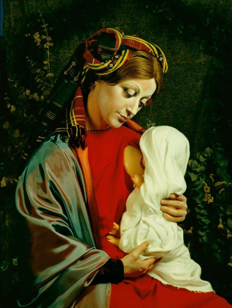 Photograph of the artist Cindy Sherman posing as the Virgin Mary in a red dress; a doll on her lap suckles from her exposed prosthetic breast.